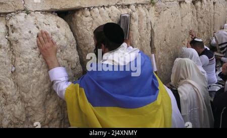 Un adoratore ebreo avvolto con la bandiera Ucraina e la preghiera Talit Shawl prega come ebrei religiosi della casta sacerdotale di Cohanim prendere parte alla messa biennale 'Birkat Kohanim' o 'benedizione sacerdotale' nella festa di Pesach (Pasqua) al Kotel a Gerusalemme, Israele. Foto Stock