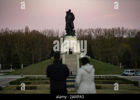 Berlino, Germania. 17th Apr 2022. I turisti si trovano di fronte alla statua di un soldato che tiene un bambino sui terreni del memoriale sovietico nel Parco Treptow. Dall'attacco russo all'Ucraina, vi è stato un numero crescente di iscrizioni con contenuto politico poste da persone sconosciute. In vista di questo sviluppo, la polizia, di concerto con i politici, ha messo a punto dei riflettori per fornire una visione migliore al buio. Credit: Paul Zinken/dpa/Alamy Live News Foto Stock