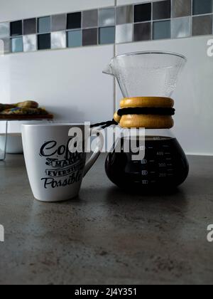 Wroclaw, Polonia - Aprile 2021: Caraffa di caffè Chemex piena di caffè e tazza bianca sul piano di lavoro della cucina Foto Stock