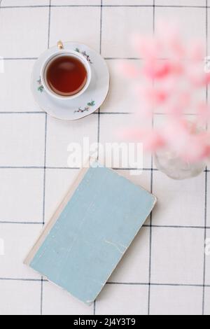 interni dal design moderno di un accogliente soggiorno con piante secche in vaso, libro e tè sul tavolo Foto Stock