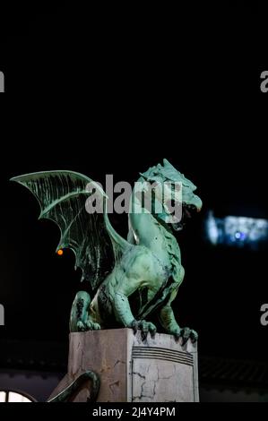 Vista sul famoso ponte del drago e la statua del drago Zmajski di notte con il castello di Lubiana sullo sfondo in Slovenia, Europa. Foto Stock