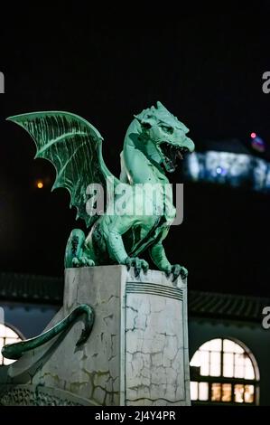 Vista sul famoso ponte del drago e la statua del drago Zmajski di notte con il castello di Lubiana sullo sfondo in Slovenia, Europa. Foto Stock