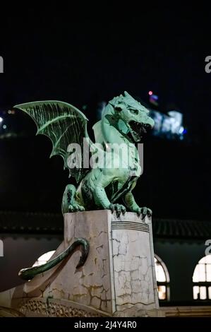 Vista sul famoso ponte del drago e la statua del drago Zmajski di notte con il castello di Lubiana sullo sfondo in Slovenia, Europa. Foto Stock