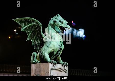 Vista sul famoso ponte del drago e la statua del drago Zmajski di notte con il castello di Lubiana sullo sfondo in Slovenia, Europa. Foto Stock