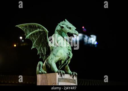 Vista sul famoso ponte del drago e la statua del drago Zmajski di notte con il castello di Lubiana sullo sfondo in Slovenia, Europa. Foto Stock
