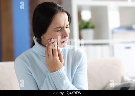 Giovane donna con grave mal di denti a casa Foto Stock