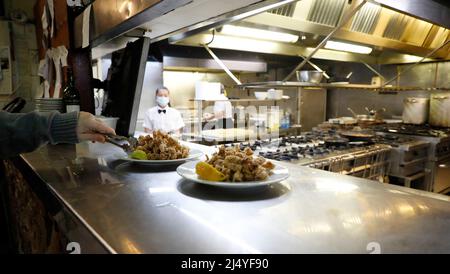 Palma, Spagna. 18th Apr 2022. Toni, cameriere del ristorante 'Sa Pressa' con cucina tipica maiorchina, serve una tapa con calamari fritti l'ultimo giorno delle vacanze pasquali. Credit: Clara Margais/dpa/Alamy Live News Foto Stock