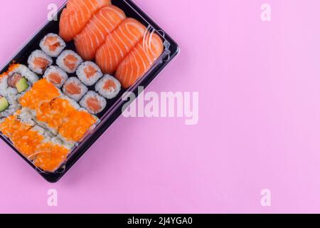 Scatola per la consegna del sushi al salmone con maki e california su sfondo rosa Foto Stock