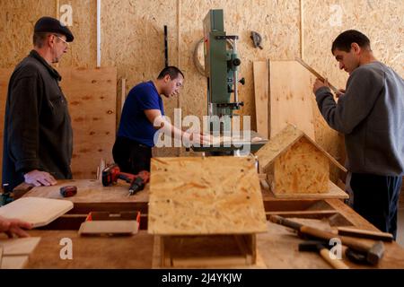 VILSHANY, UCRAINA - 15 APRILE 2022 - gli uomini sono visti in un laboratorio di lavorazione del legno in una pensione locale per bambini disabili e mentalmente sfidati Foto Stock