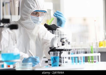 Lo scienziato in tuta protettiva studia liquidi tossici velenosi in laboratorio Foto Stock