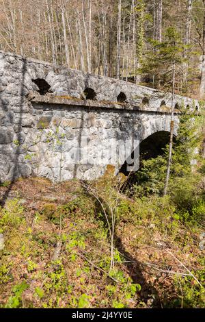 Riedern, Canton Glarona, Svizzera, 13 aprile 2022 storico ponte in pietra in una foresta attraverso un piccolo canyon Foto Stock