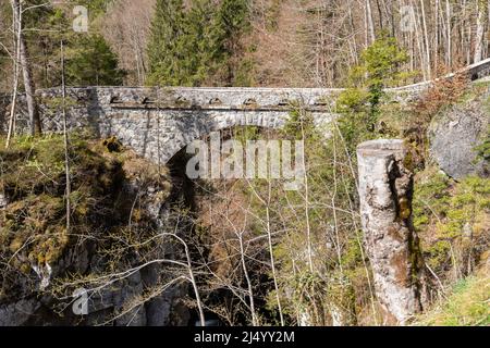 Riedern, Canton Glarona, Svizzera, 13 aprile 2022 storico ponte in pietra in una foresta attraverso un piccolo canyon Foto Stock