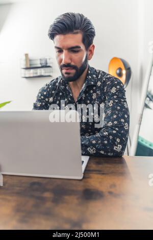Giovane uomo caucasico che lavora dall'ufficio sul suo laptop. Foto di alta qualità Foto Stock
