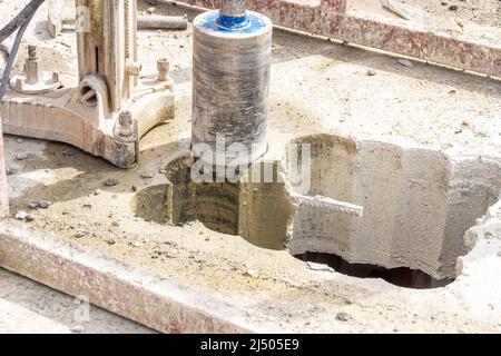 foratura su pavimento o soffitto in calcestruzzo con carro di perforazione e punta di perforazione, messa a fuoco selettiva Foto Stock