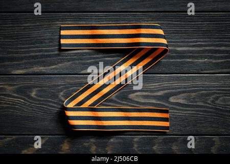 Lettera Z realizzata con nastro a strisce George su sfondo di legno scuro, logo Z per la forza militare russa, simbolo militare e segno della Russia utilizzato in Russia-U. Foto Stock