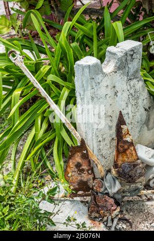 Un'ancora arrugginita e conchiglie stagne fuori dal Museo Bimini sulla Kings Highway nelle Bahamas. Foto Stock