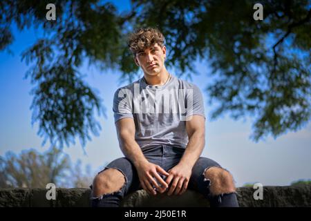 Fiducioso giovane biondo ritratto uomo, estate alberi sfondo. Spazio di copia Foto Stock