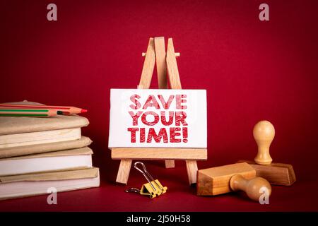 Risparmiate tempo. Cavalletto in miniatura e libri su sfondo rosso. Foto Stock