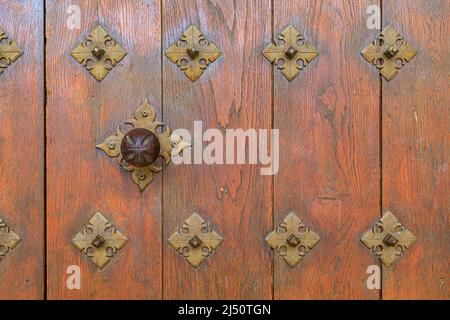 Decorazioni in ferro ornato e maniglia sulla vecchia porta di legno della chiesa di Santa Maria la Real a Olite, Spagna Foto Stock