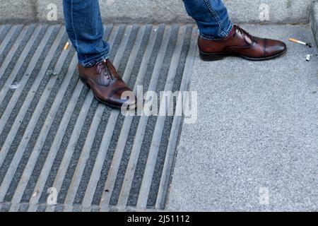 scarpe classiche in pelle da uomo accanto ai mozziconi di sigaretta Foto Stock