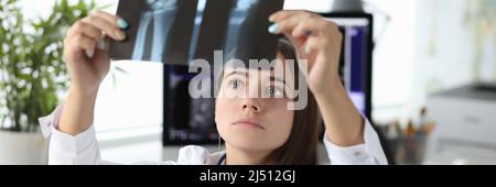 Medico donna che guarda raggi di mano in clinica Foto Stock