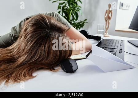 La donna stanca dorme mentre lavora a distanza a casa, burnout di lavoro in eccesso, freelance lavora a distanza sul posto di lavoro domestico Foto Stock