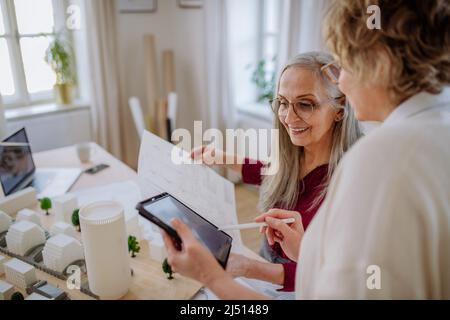 Donne mature eco architetti con progetti che lavorano su tablet insieme in ufficio. Foto Stock