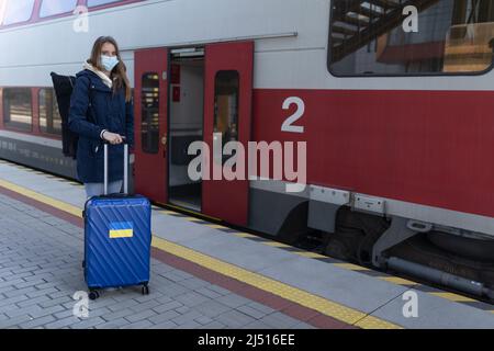 Giovane donna Ucraina con valigia in attesa di treno alla stazione ferroviaria ucraino concetto di guerra. Foto Stock