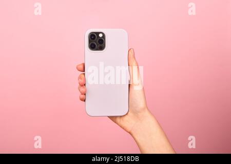 Smartphone bianco femmina con custodia in morbido silicone, vista posteriore . Custodia del telefono mock in su isolato su sfondo blu ombra da una pianta Foto Stock