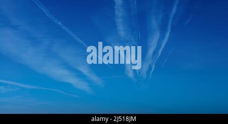 L'aeroplano contrasta con il cielo blu con la nuvola bianca. Percorso di condensazione Jet Plane. Nuvole linee di aerei Foto Stock