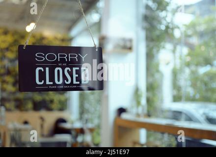 Il cartello del Business Coffee Shop è appeso alla porta e mostra "Siamo chiusi" con caffè e ristorante sfocato sfondo bokeh. Foto Stock