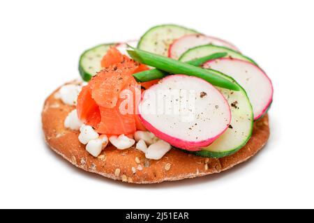 Panino Cracker croccante con salmone, cetriolo, piatto, formaggio Cottage e cipolle verdi - isolato su bianco. Colazione facile. Panini veloci e sani. Croccante con gustoso ripieno - isolamento Foto Stock