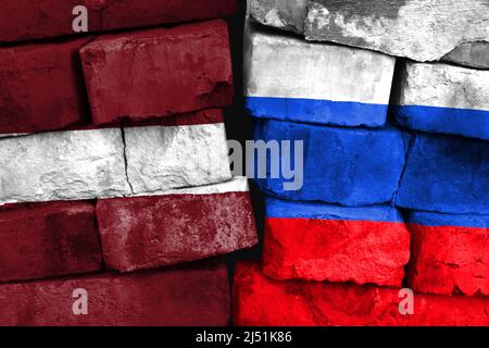 Concetto del rapporto tra Lettonia e Russia con due bandiere dipinte su un muro di mattoni danneggiato Foto Stock