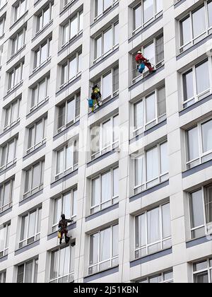 Gli scalatori industriali lavano le finestre su un enorme edificio residenziale. Lavorare in quota richiede abilità e abilità. Foto Stock