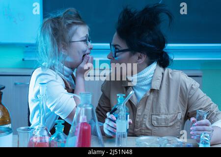 Divertente insegnante e bambina durante la lezione di chimica miscelazione di sostanze chimiche in un laboratorio Foto Stock