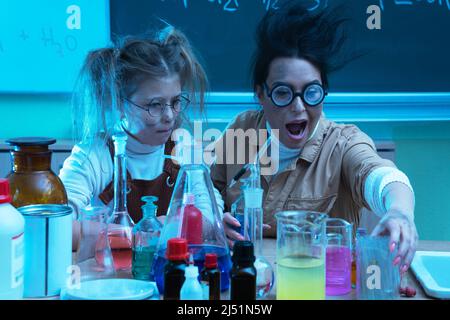 Divertente insegnante e bambina durante la lezione di chimica miscelazione di sostanze chimiche in un laboratorio Foto Stock