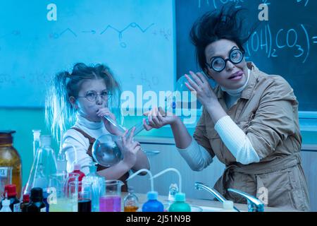 Divertente insegnante e bambina durante la lezione di chimica miscelazione di sostanze chimiche in un laboratorio Foto Stock