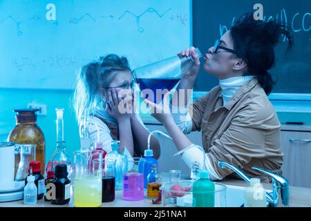 Divertente insegnante e bambina durante la lezione di chimica miscelazione di sostanze chimiche in un laboratorio Foto Stock