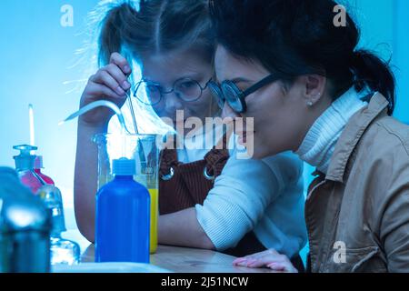 Divertente insegnante e bambina durante la lezione di chimica miscelazione di sostanze chimiche in un laboratorio Foto Stock