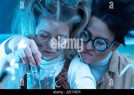 Divertente insegnante e bambina durante la lezione di chimica miscelazione di sostanze chimiche in un laboratorio Foto Stock