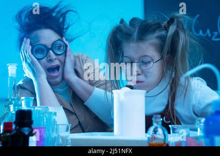 Divertente insegnante e bambina durante la lezione di chimica miscelazione di sostanze chimiche in un laboratorio Foto Stock