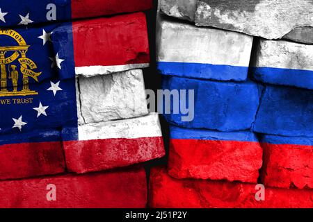 Concetto del rapporto tra lo Stato della Georgia e la Russia con due bandiere dipinte su un muro di mattoni danneggiato Foto Stock