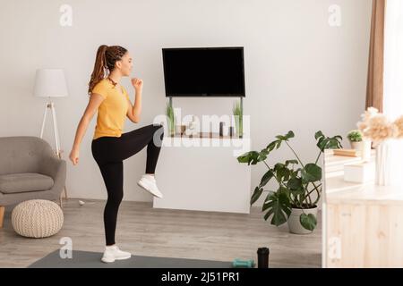 African American Lady fare ginocchio a gomito gamba esercizio interno Foto Stock