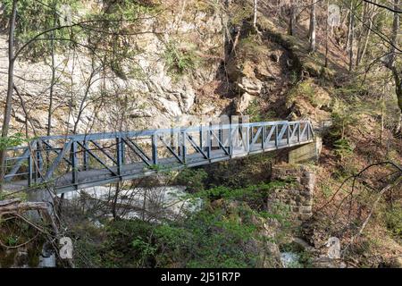 Weesen, Svizzera, 13 aprile 2022 piccolo ponte pedonale su un piccolo canyon su un sentiero escursionistico Foto Stock