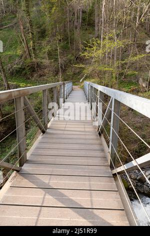 Weesen, Svizzera, 13 aprile 2022 piccolo ponte pedonale su un piccolo canyon su un sentiero escursionistico Foto Stock