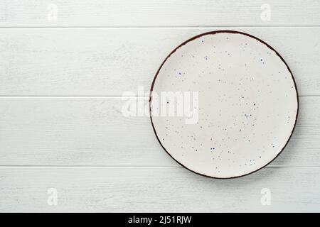 Piastra bianca vuota in ceramica. Rustico set vintage di piatto bianco, cucchiaio di legno su sfondo di legno bianco chiaro. Argenteria vintage Zero Waste. Piatto vuoto Foto Stock