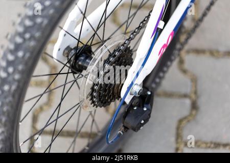 Una bicicletta bianca per bambini, un primo piano del deragliatore e una ruota libera della ruota posteriore. Sfondo sfocato, foto scattata in luce naturale e soffusa Foto Stock