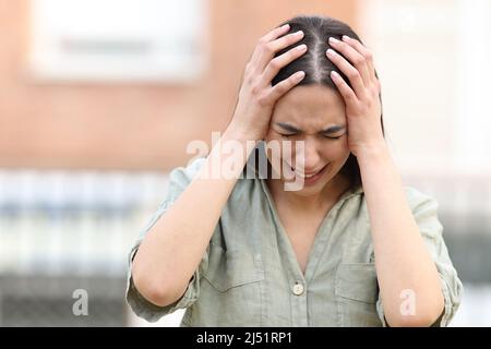 Donna triste che si lamenta disperatamente in piedi per strada Foto Stock