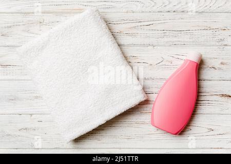 Boccetta per shampoo cosmetico con asciugamani su un tavolo colorato. Sfondo bagno, accessori per la cura delle mani e del corpo. Foto Stock