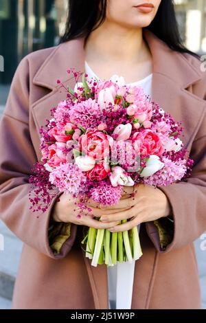 Giovane donna con bouquet da sposa in tonalità lilla rosa in giacinto, tulipani e gypsofila. Foto Stock